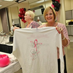 Lady holding up a tee shirt designed with the fundraiser logo